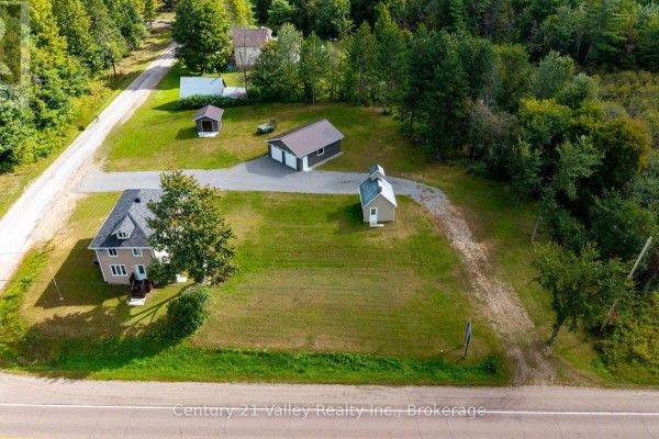 Rear exterior view of the house with tan siding and a wooden deck. - 387 Sell Road, North Algona Wilberforce