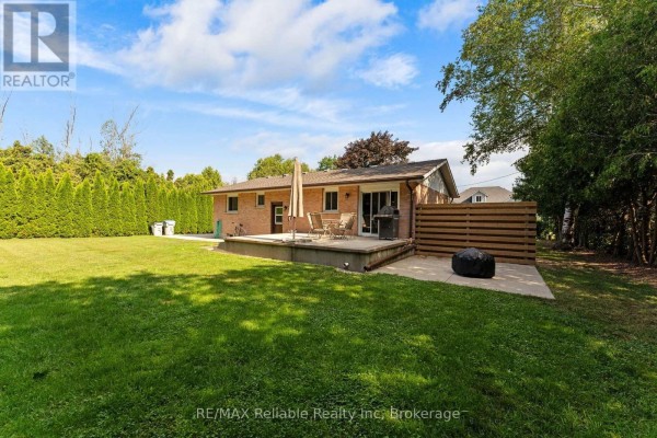 Backyard view of a brick bungalow with a wooden deck and patio. - 38823 Vienna Street, Bluewater