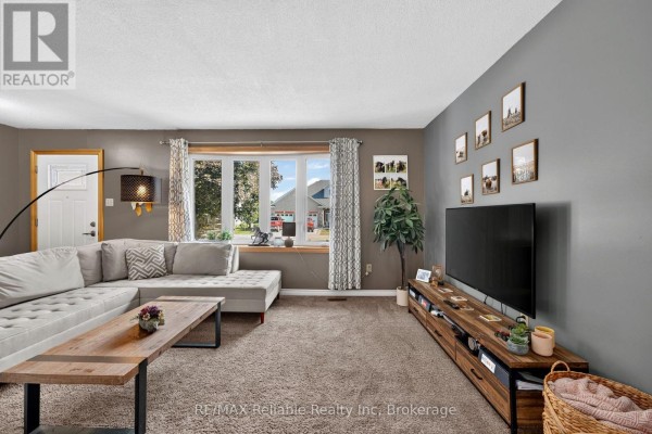 Living room with a large gray sectional, wood entertainment unit, and window view. - 38823 Vienna Street, Bluewater