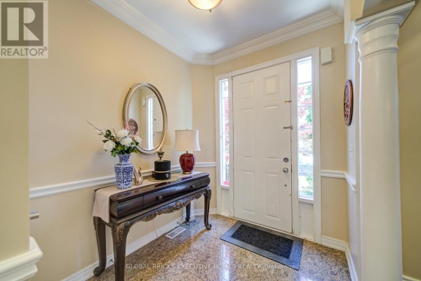 Interior foyer with a dark wood console table, oval mirror, and cream walls. - 3885 Eglinton Avenue, Mississauga