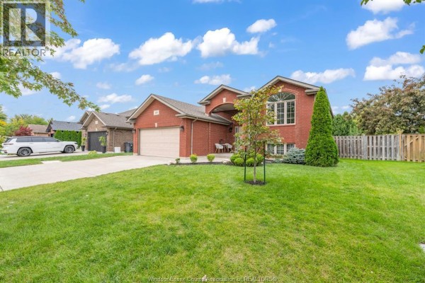 Wide angle exterior shot showing the red brick house, driveway, and lawn. - 389 Donlon, Lasalle