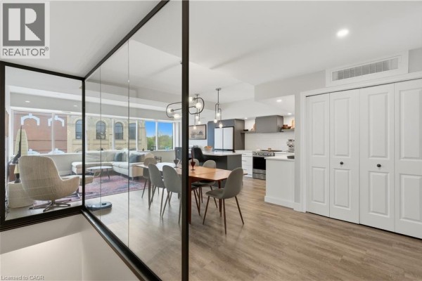 View of a dining area and kitchen through a glass partition, with living room beyond. - 389 Dundas Street, Woodstock