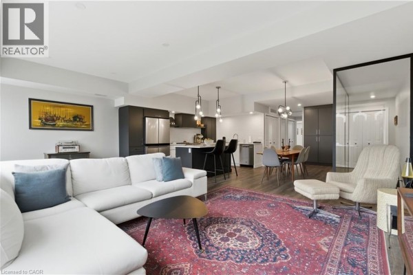 Living room with white sectional sofa, Persian rug, and view of the kitchen island. - 389 Dundas Street, Woodstock