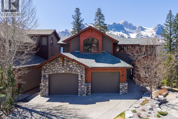 Exterior of a large house with a stone-accented facade and two garage doors. - 389 Eagle Heights, Canmore