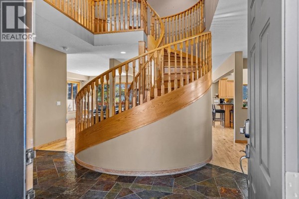 Entrance foyer with a slate tile floor and a prominent wooden spiral staircase. - 389 Eagle Heights, Canmore