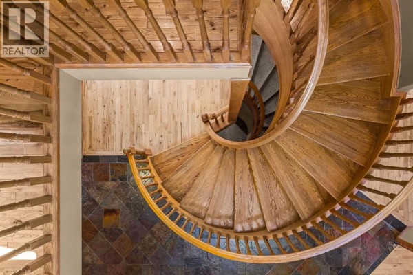 Overhead view of a curved wooden spiral staircase with light wood floors. - 389 Eagle Heights, Canmore