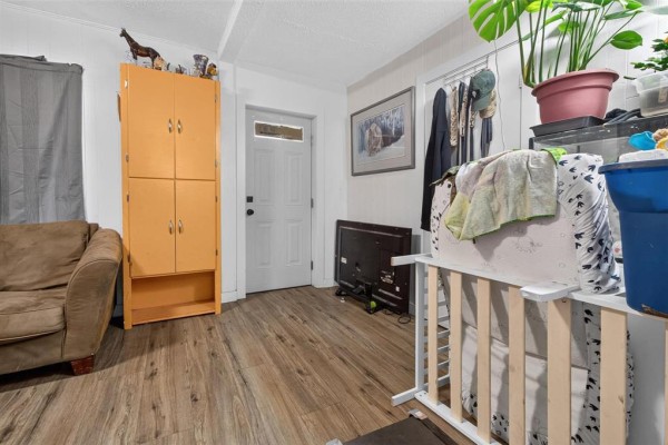Interior room with laminate flooring, beige sofa, and orange cabinet. - 389 Harbison Avenue W, Winnipeg