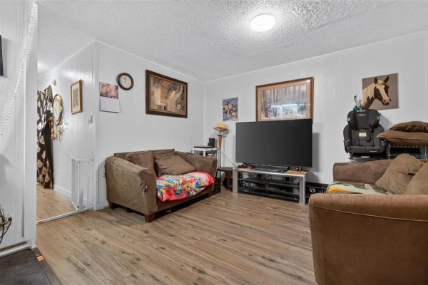 Living room with beige sofas, television, and wood laminate flooring. - 389 Harbison Avenue W, Winnipeg