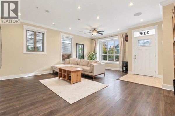 Living room with a sectional sofa, coffee table, and entryway. - 3895 Dumfries Street, Vancouver