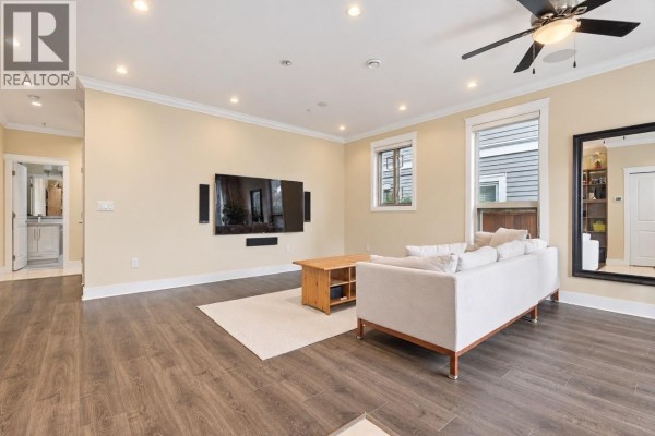 Living room with a sofa, large television, and hallway entrance. - 3895 Dumfries Street, Vancouver