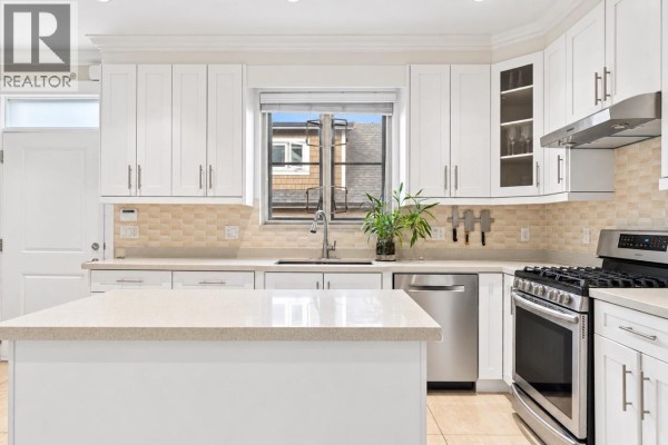 Kitchen with white cabinets, quartz countertops, and stainless steel appliances. - 3895 Dumfries Street, Vancouver