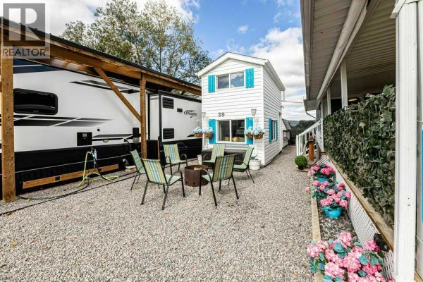 Outdoor seating area with a fire pit on a gravel pad next to a large RV and a white tiny house. - 39, 12036 Township Road 422, Rural Ponoka County