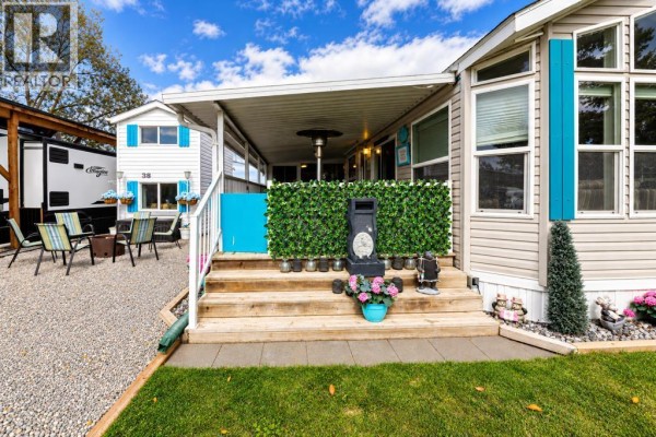 Wooden stairs leading to a covered porch with green fencing and blue accents on a mobile home. - 39, 12036 Township Road 422, Rural Ponoka County