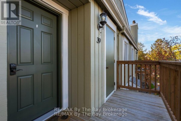 Entrance to unit 39 with dark green front door, frosted glass door, and wooden deck railing. - 39 - 19 Dawson Drive, Collingwood