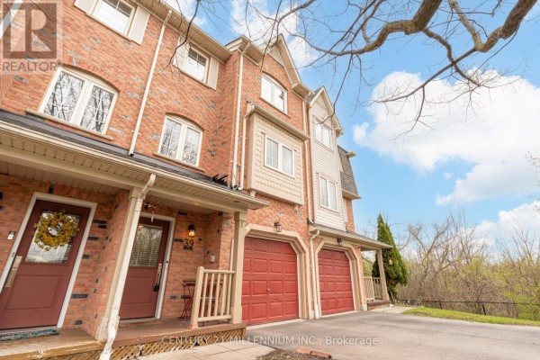 Street view of a row of brick townhouses with red garage doors and mature trees. - 39 - 7190 Atwood Lane, Mississauga