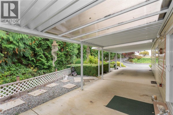 Covered concrete patio with white lattice fencing and garden views. - 39 1048 Murchie Way, Nanaimo