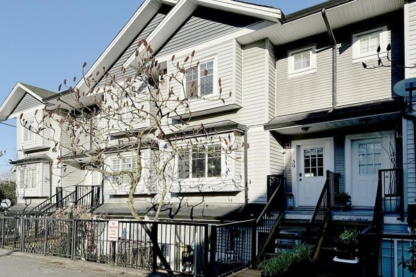 Exterior of a townhouse complex with light grey siding and white trim. - 39 11255 132 Street, Surrey