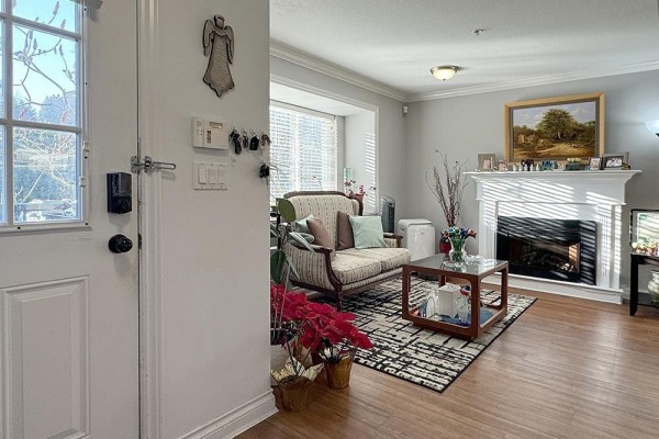 Entryway with a white door and view into the living room. - 39 11255 132 Street, Surrey