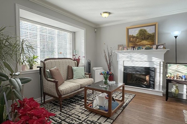 Living room with a fireplace, bay window, loveseat, and hardwood floors. - 39 11255 132 Street, Surrey