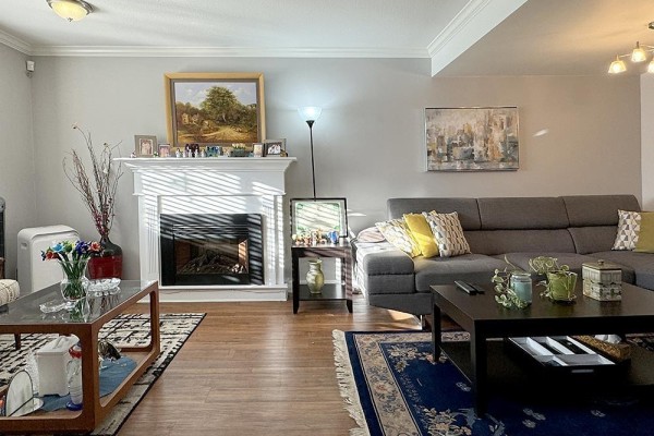 Living room with a fireplace, sectional sofa, and hardwood floors. - 39 11255 132 Street, Surrey