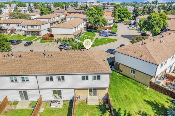 Aerial view of the backyards and rear entrances of multiple townhouses with green grass and fences. - #39 14511 52 St Nw, Edmonton