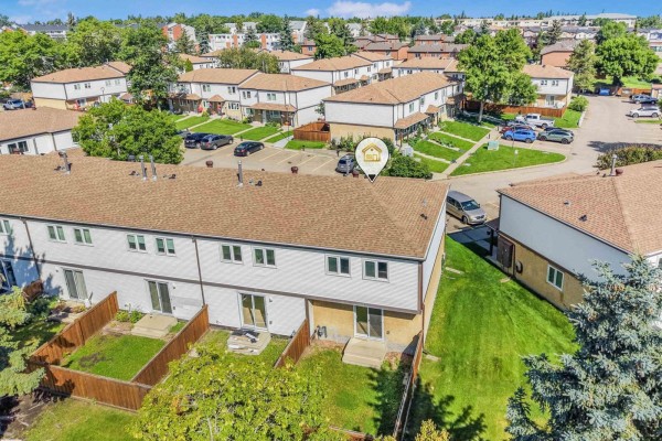 Aerial view of the rear of townhouses, showing backyards, fences, and adjacent parking lot. - #39 14511 52 St Nw, Edmonton