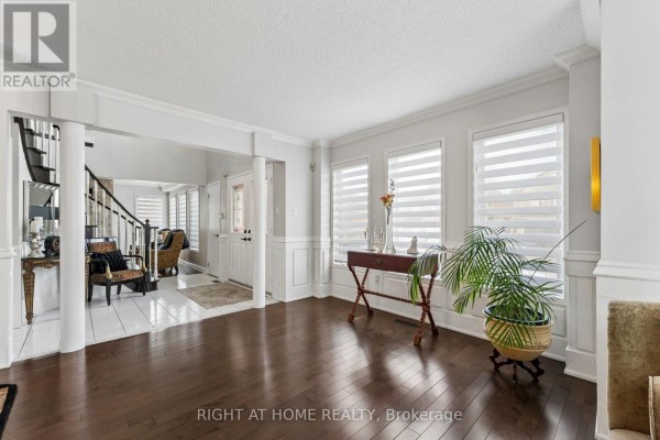Living room with dark hardwood floors, white walls, and large windows with roller blinds. - 39 Banner Road, Brampton