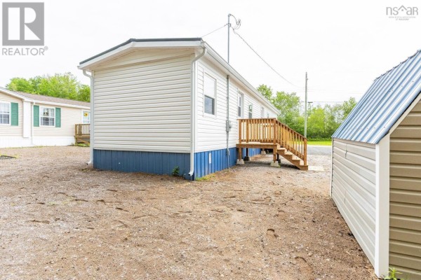 A kitchen area with light wood cabinets, dark countertops, a double sink, a white refrigerator, and an adjoining living space with wood floors. - 39 Beattie Drive, Windermere