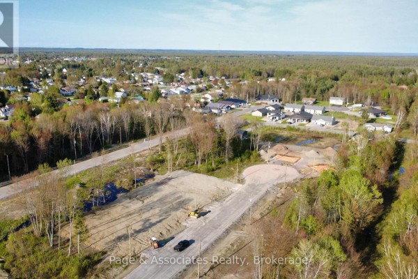 Aerial view of a new housing development with surrounding woods and town. - 39 Brianne Court, West Nipissing