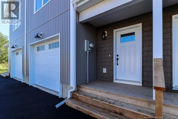 Close-up of a white garage door and a white front door on a grey townhouse. - 39 Downsview Drive, Saint John