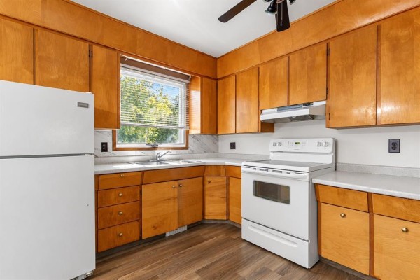 Kitchen featuring natural wood cabinets, white appliances including a stove and refrigerator, and a window above the sink. - 39 First Avenue N, Blumenort