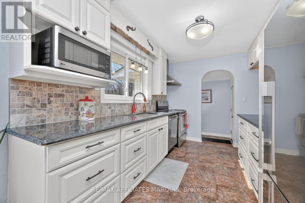 Kitchen with white cabinets, granite counters, and stainless steel appliances - 39 Golf Club Road Rideau Lakes