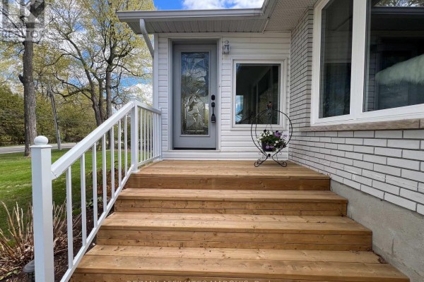 View of the paved driveway leading to the white bungalow home with a double garage. - 39 Golf Club Road, Rideau Lakes
