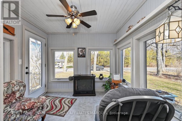 White bungalow home with brick accents, large windows, and a connected double garage. - 39 Golf Club Road, Rideau Lakes