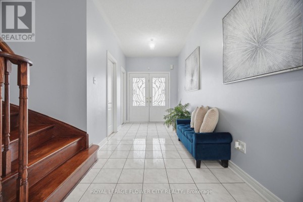 Foyer of 39 Hadfield Circle featuring light blue walls, white tile floor, and double glass doors. - 39 Hadfield Circle, Brampton