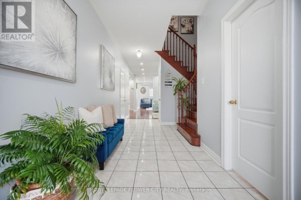 Foyer of 39 Hadfield Circle with wood stairs, light blue walls, and a blue velvet bench. - 39 Hadfield Circle, Brampton