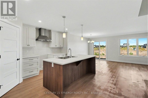 Open concept kitchen and living area with a large island, white cabinets, stainless steel appliances, and large windows. - 39 Helen Street, North Stormont