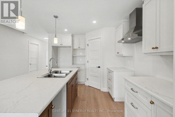 Kitchen island with a double sink, white countertops, dark wood base cabinets, and white upper cabinets. - 39 Helen Street, North Stormont