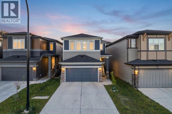 Front view of a modern two-story house with blue and grey siding, two garage doors, and a wide driveway at dusk. - 39 Herron Rise Ne, Calgary