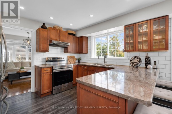 Kitchen with wood cabinets, stainless steel appliances, a granite countertop, and a window overlooking greenery. - 39 Howard Drive, Oro Medonte