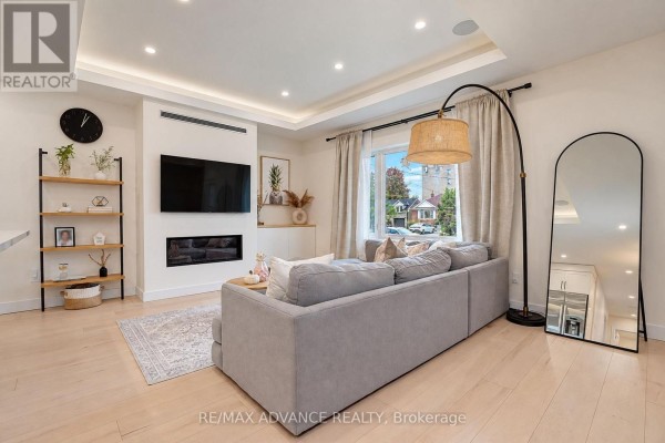 Living room with a sectional sofa, fireplace, mounted television, and floor-to-ceiling window. - 39 Janet Boulevard, Toronto