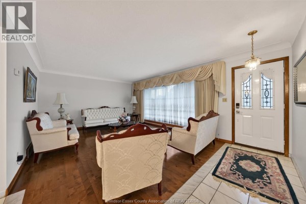 Living room with white sofas, armchairs, hardwood floors, and a large bay window. - 39 Johnson Avenue, Leamington