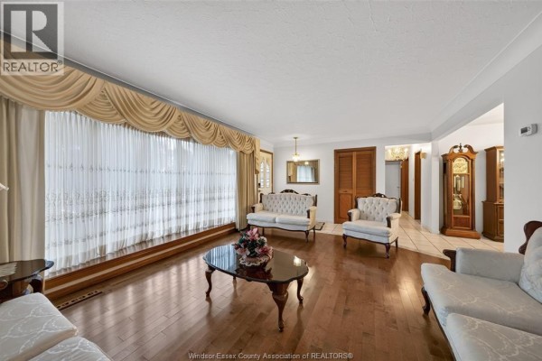 Living room with ornate white furniture, dark wood coffee table, hardwood floors, and entryway. - 39 Johnson Avenue, Leamington