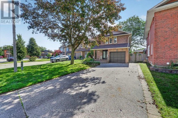 View down the paved driveway towards the two-storey brick house. - 39 Longfellow Court, Whitby