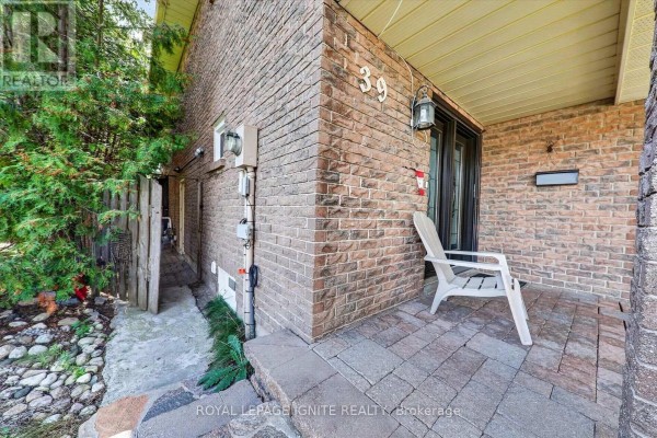 Close-up of the porch with brick walls, paved flooring, and a white chair. - 39 Longfellow Court, Whitby