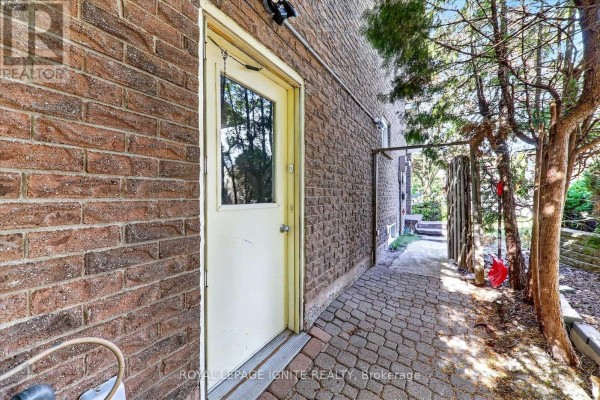 Exterior view of the brick house showing a yellow door and a paved walkway. - 39 Longfellow Court, Whitby