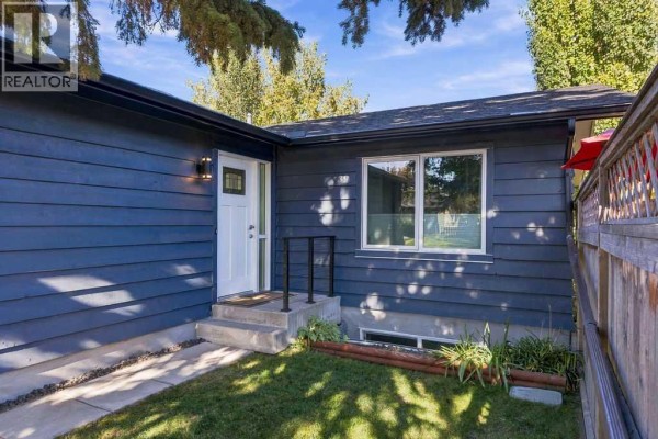 Side exterior of the blue house showing a white front door and a small set of concrete stairs. - 39 Midridge Close Se, Calgary