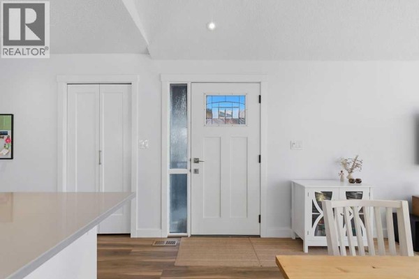 Interior view of the front entrance with a white door, glass sidelight, and wood flooring. - 39 Midridge Close Se, Calgary