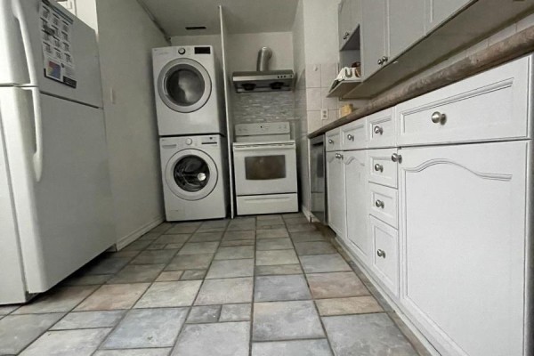 Kitchen with white cabinets, stainless steel appliances including stacked washer and dryer, and tiled floor. - 39 Richardson Drive S, Aurora