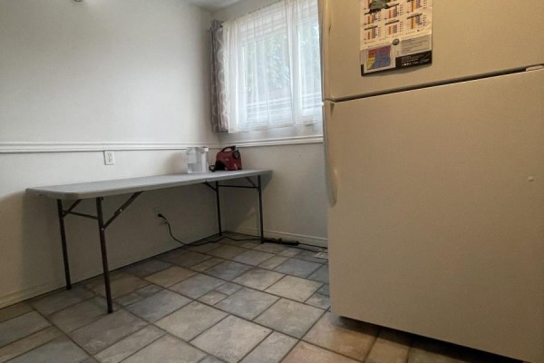 Room with folding table against white wall, window with sheer curtains, and white refrigerator. - 39 Richardson Drive S, Aurora